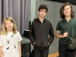 Three young people standing together indoors.