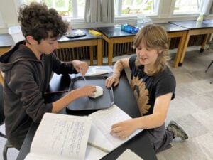 Students conduct science experiment with paper and tray.