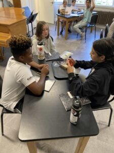 Children discussing around a table with notebooks.