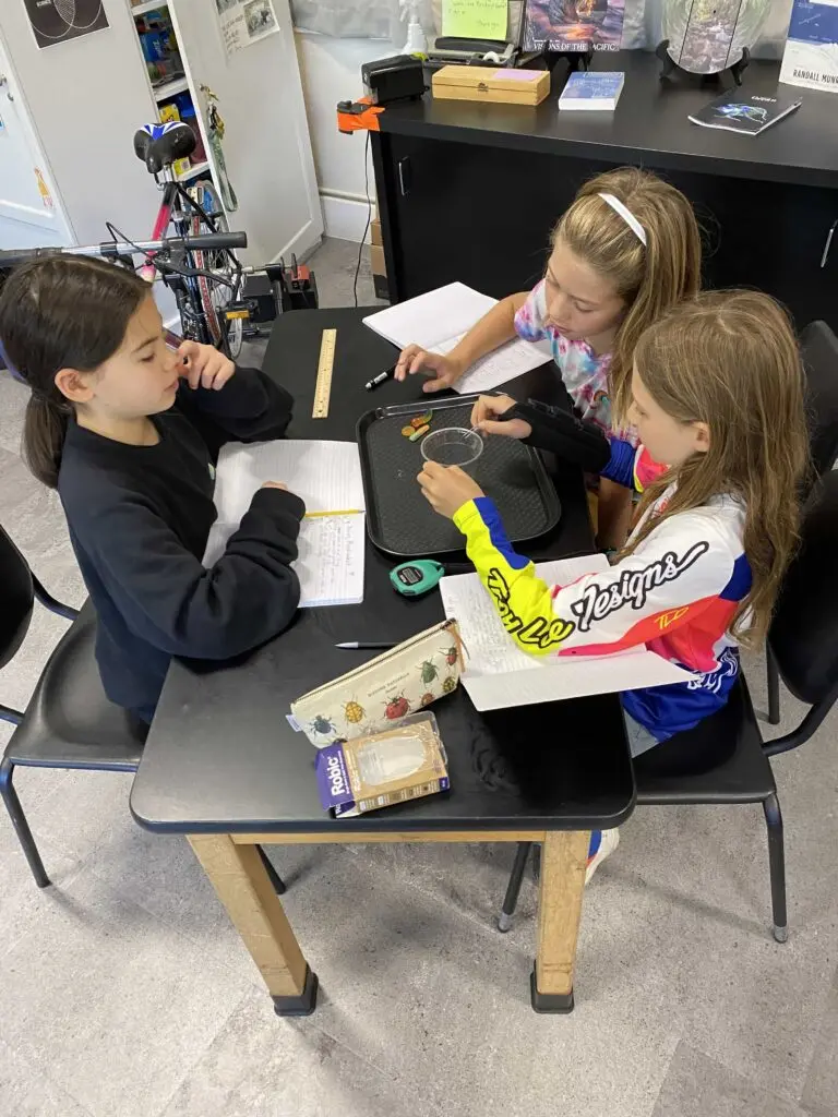 Three children performing a science experiment at a table.