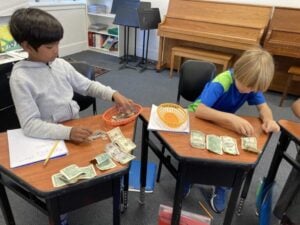 Children counting money at school desks.