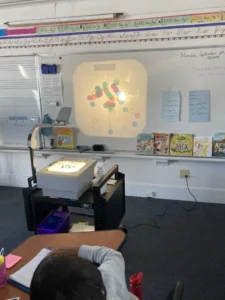 Classroom overhead projector displays geometric pattern.