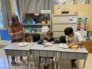 Kids decorating cakes in a classroom setting.
