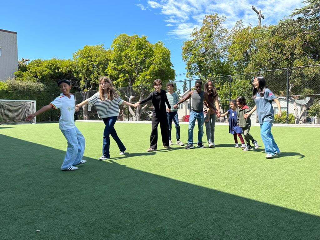 Group playing holding hands on a sunny field.