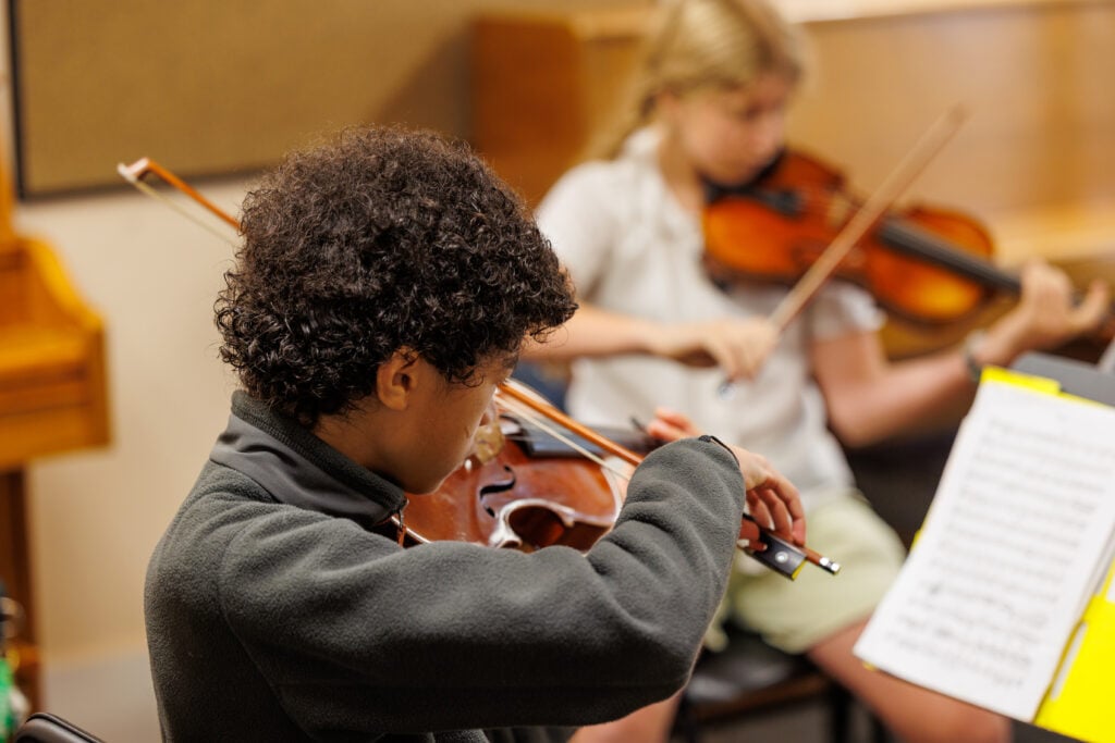 Children playing violins in music class.