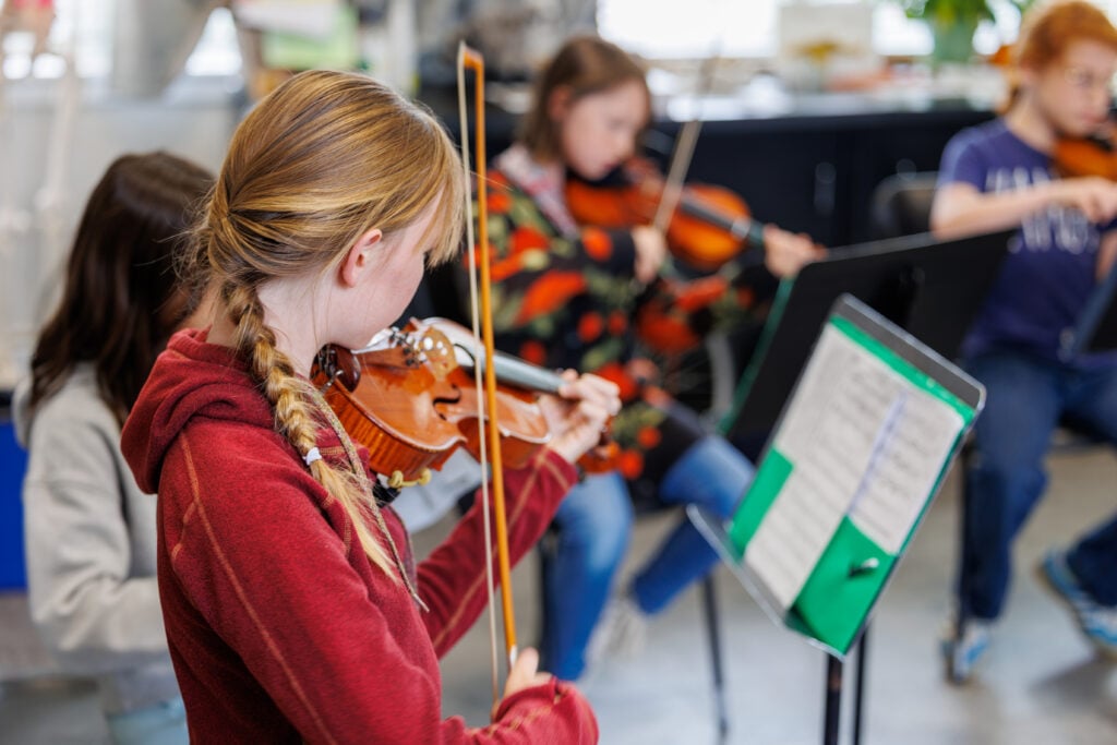 Children playing violins in music class.