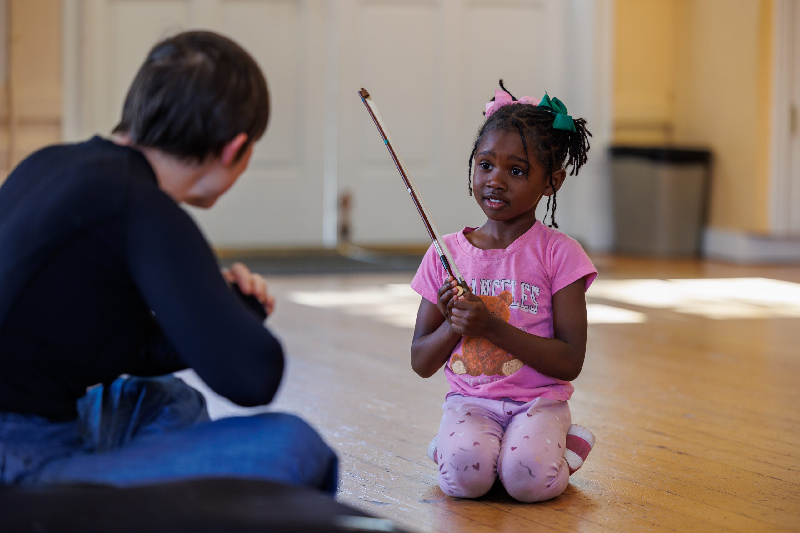 Child with a violin bow in a classroom.
