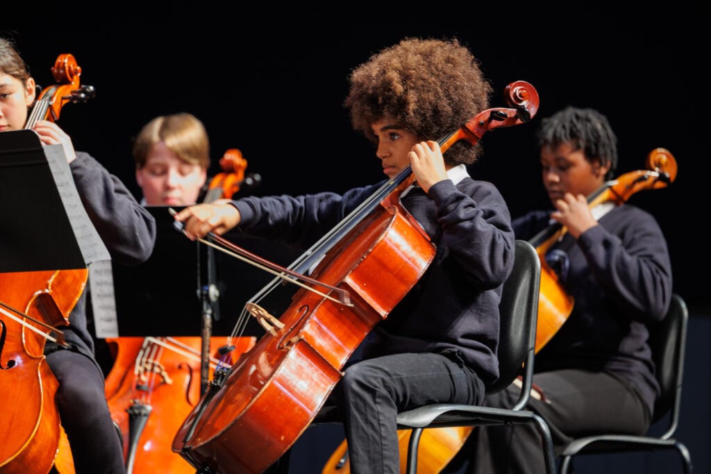 Children playing cellos in a school orchestra.