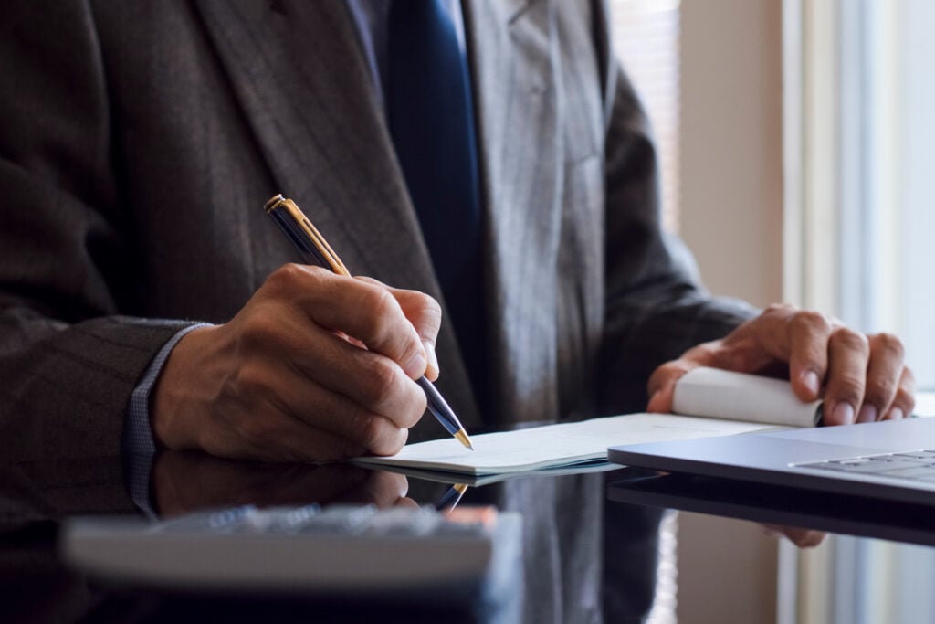 Person writing a check at a desk.