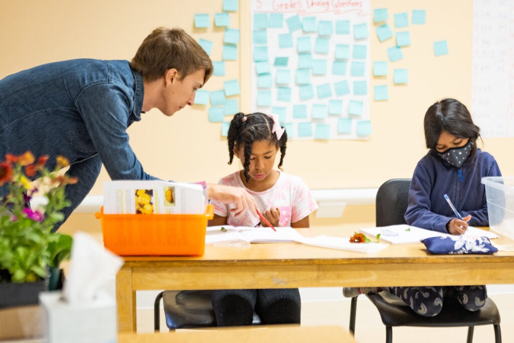 Teacher assisting students in classroom activity.
