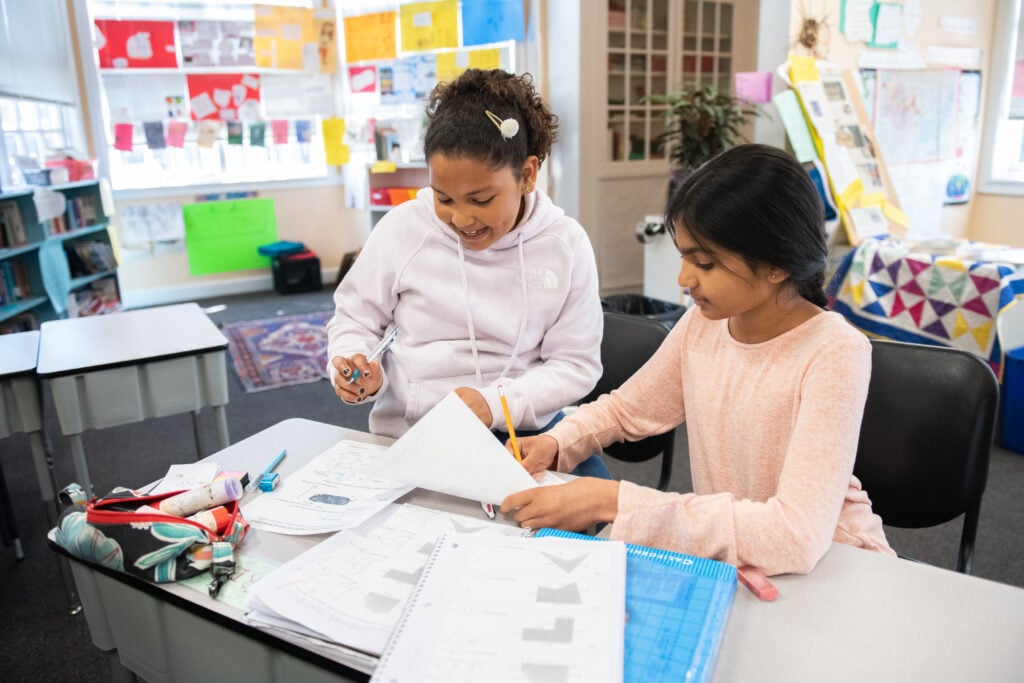 Two students collaborating on a school project in classroom.