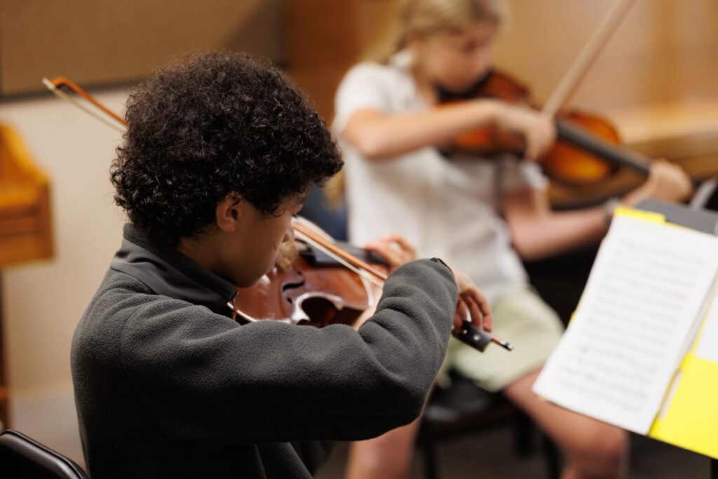 Crowden students practicing violin in music class.