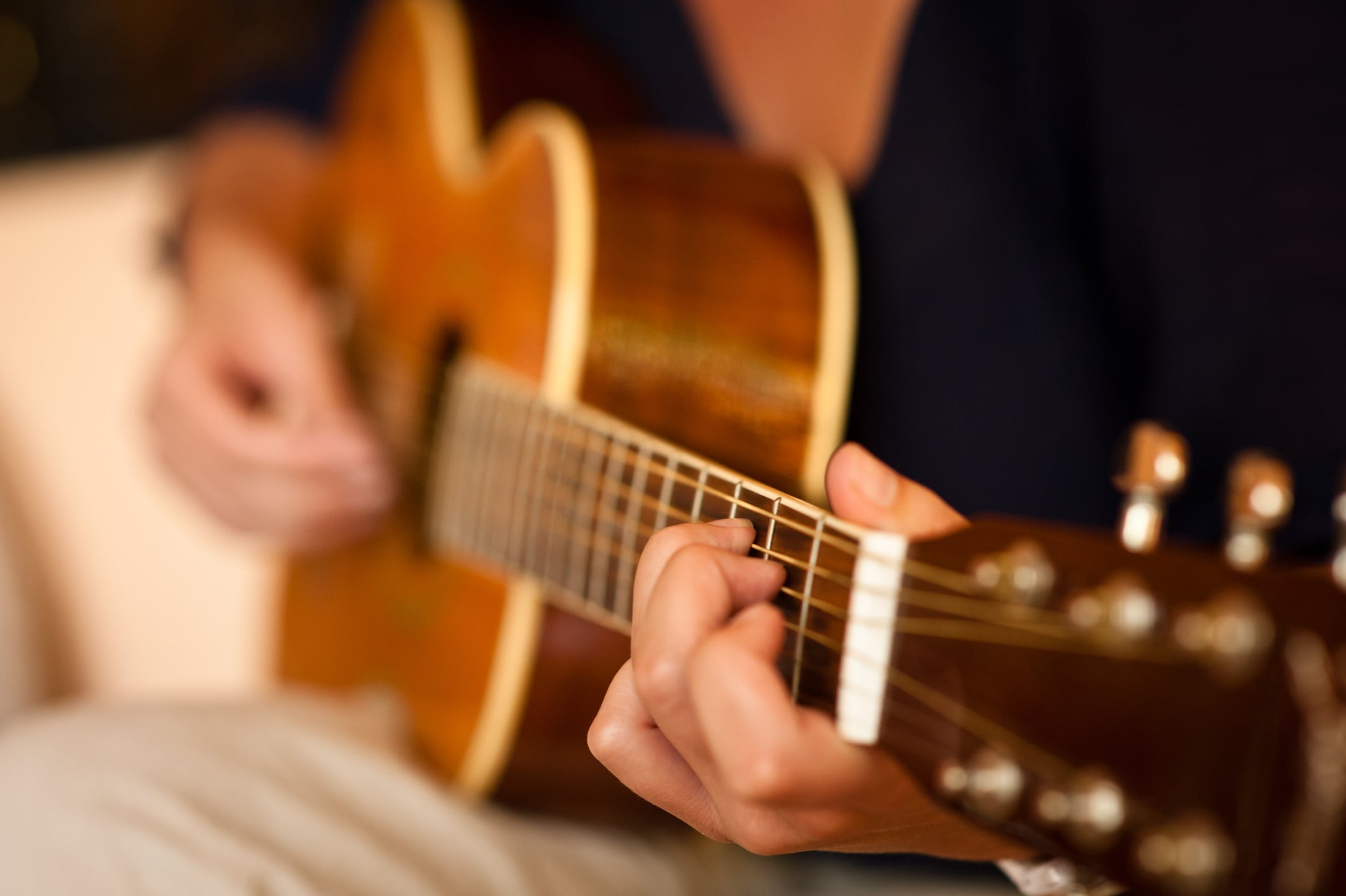 Person playing acoustic guitar with focus on strings.