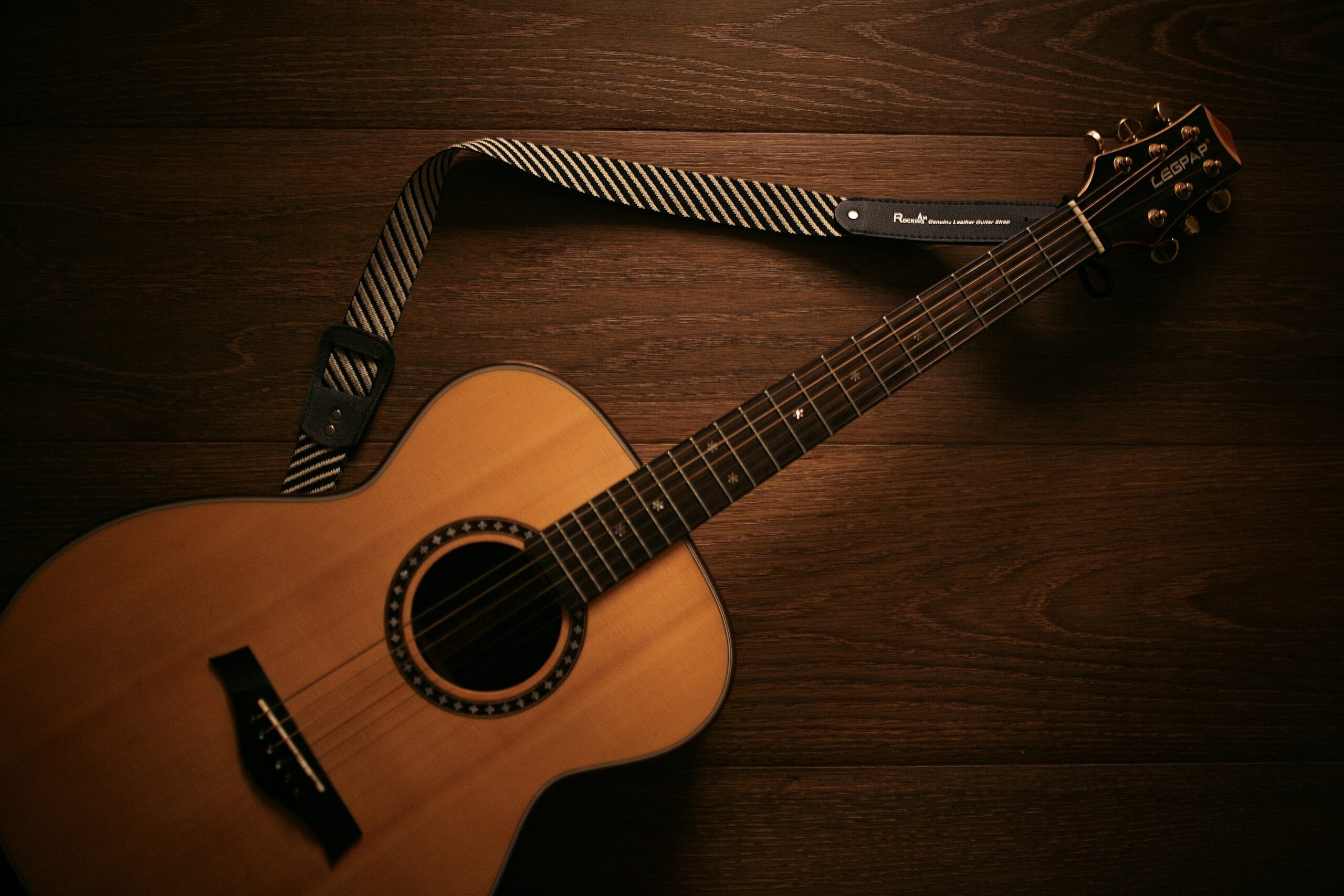 Acoustic guitar with strap on wooden surface