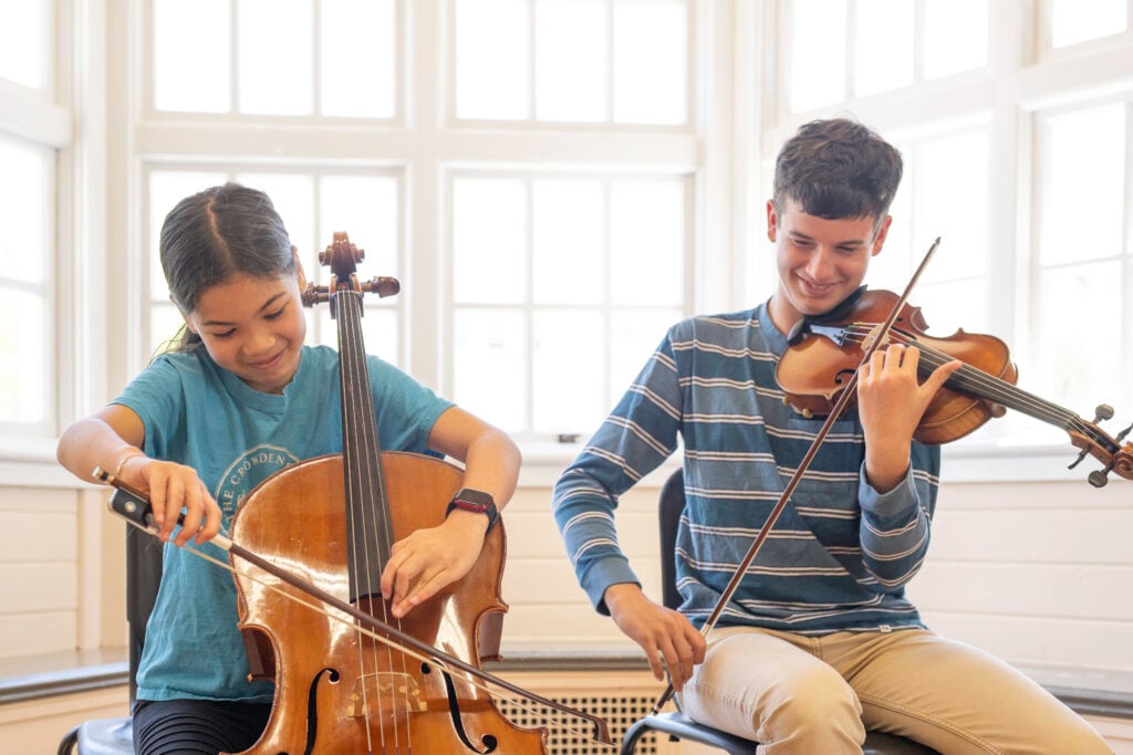 Two children playing cello and violin indoors
