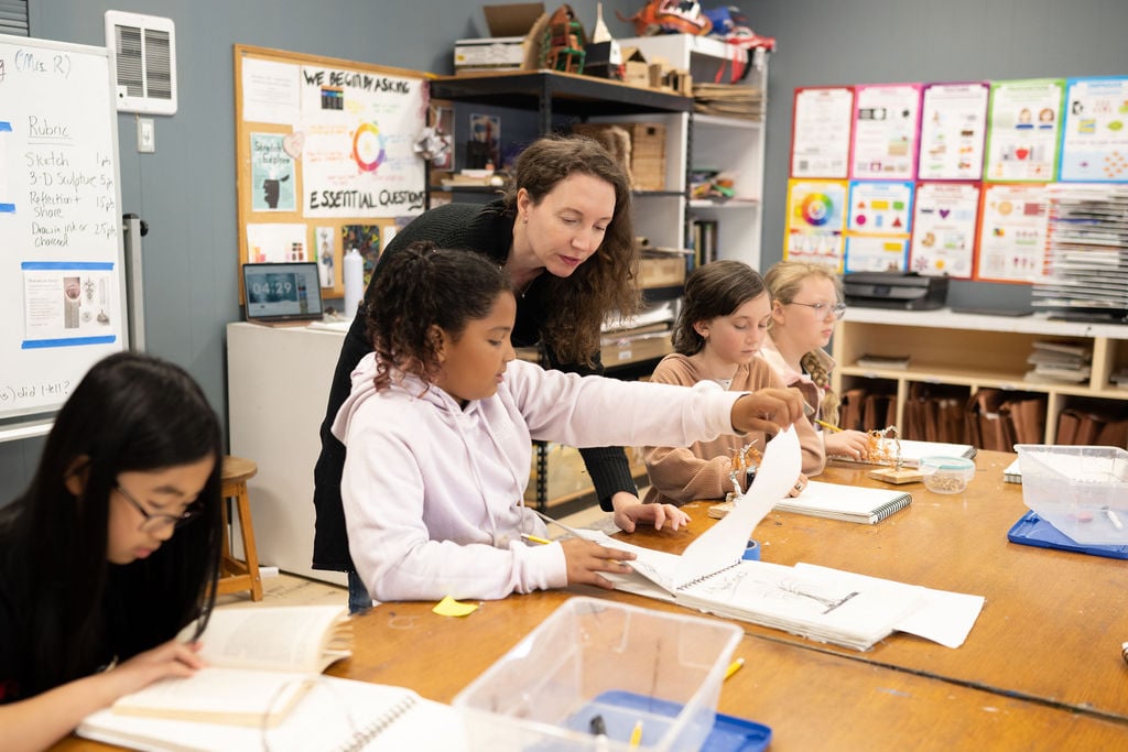 Teacher assisting students with art projects in classroom