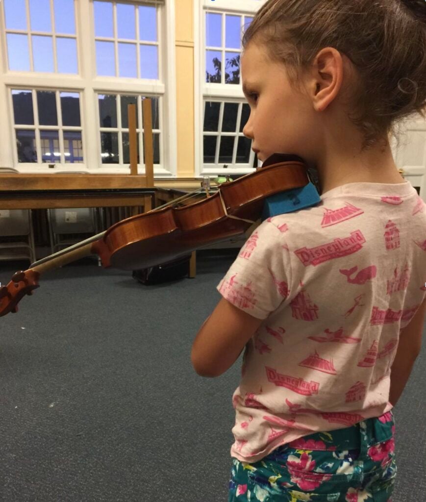 Young girl holding a violin in a music classroom